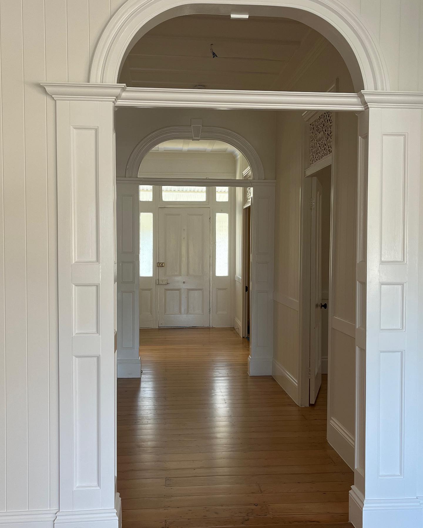 Restored Queenslander hallway with arched doorways and timber floors